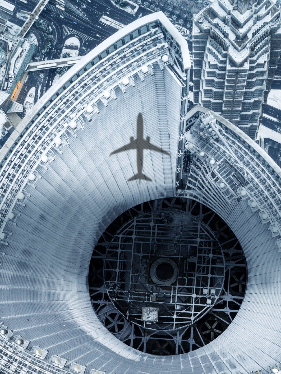 Schatten eines Passagierflugzeugs fällt auf die Fassade eines Hochhauses inmitten einer modernen Metropole